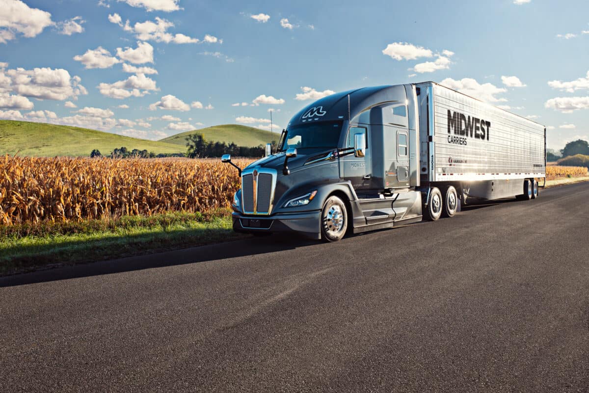 Midwest Carriers truck parked on the side of the road next to a field of corn