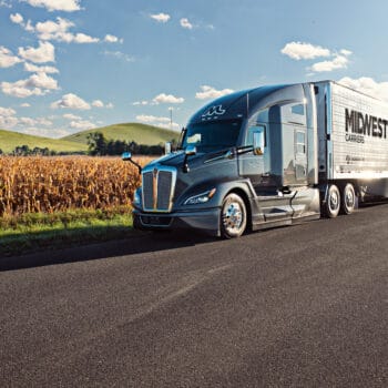 Midwest Carriers truck parked on the side of the road next to a field of corn