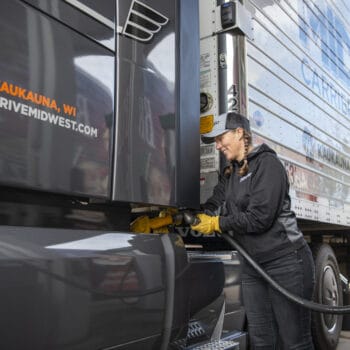 Female truck driver fills the fuel tank of a Midwest Carriers truck