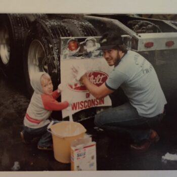 Man and child washing the trailer of a truck