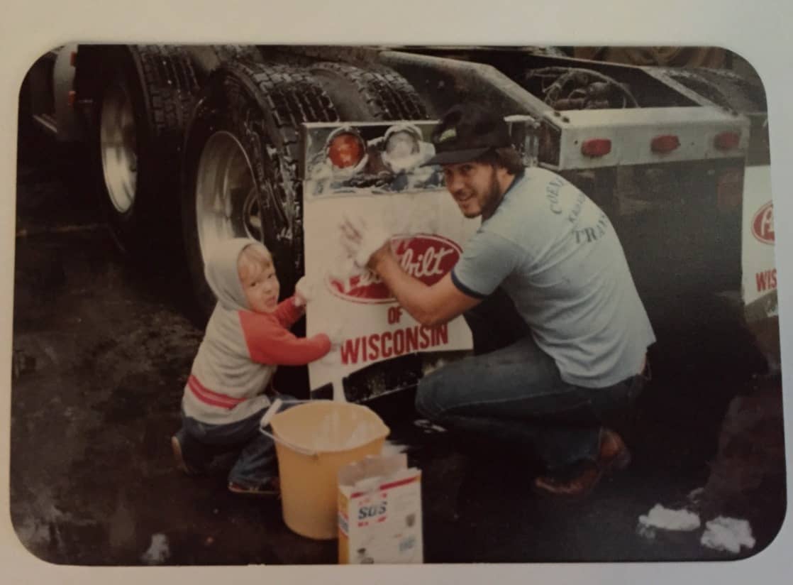 Man and child washing the trailer of a truck