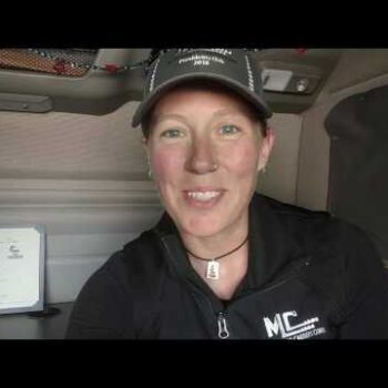 Female truck driver smiling in truck cab