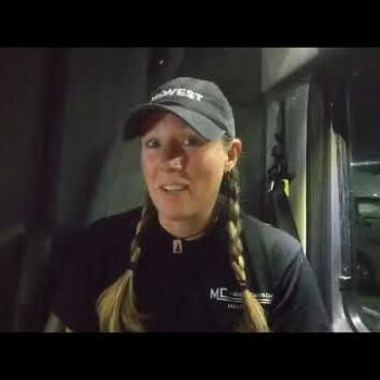 Female truck driver smiling in truck cab
