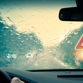 Front view window of car with caution sign visible during bad weather